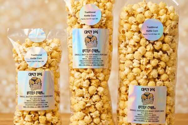 Three clear bags of Crazy Dog kettle corn with holographic labels on wood table — gourmet popcorn packaging